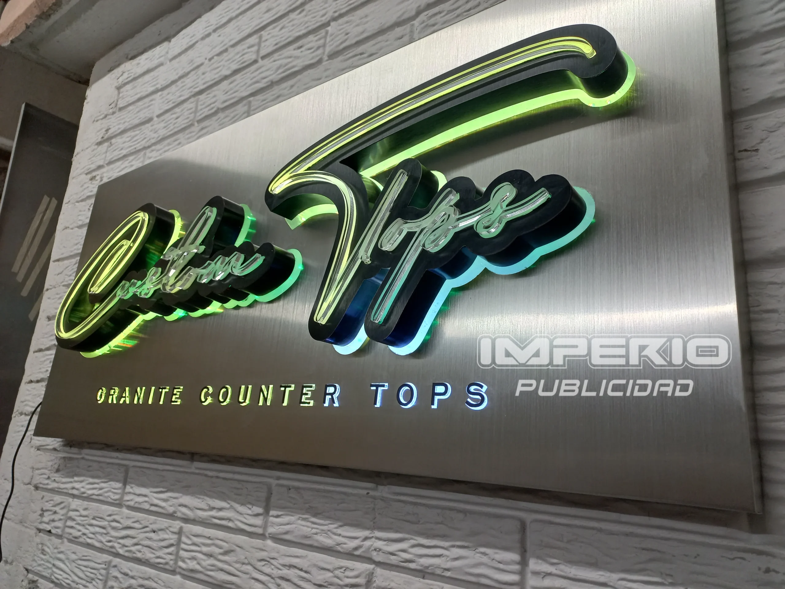Letrero luminoso 3D con iluminación LED y acabado en acero cepillado instalado en muro blanco, fabricado por Imperio Publicidad CDMX.
