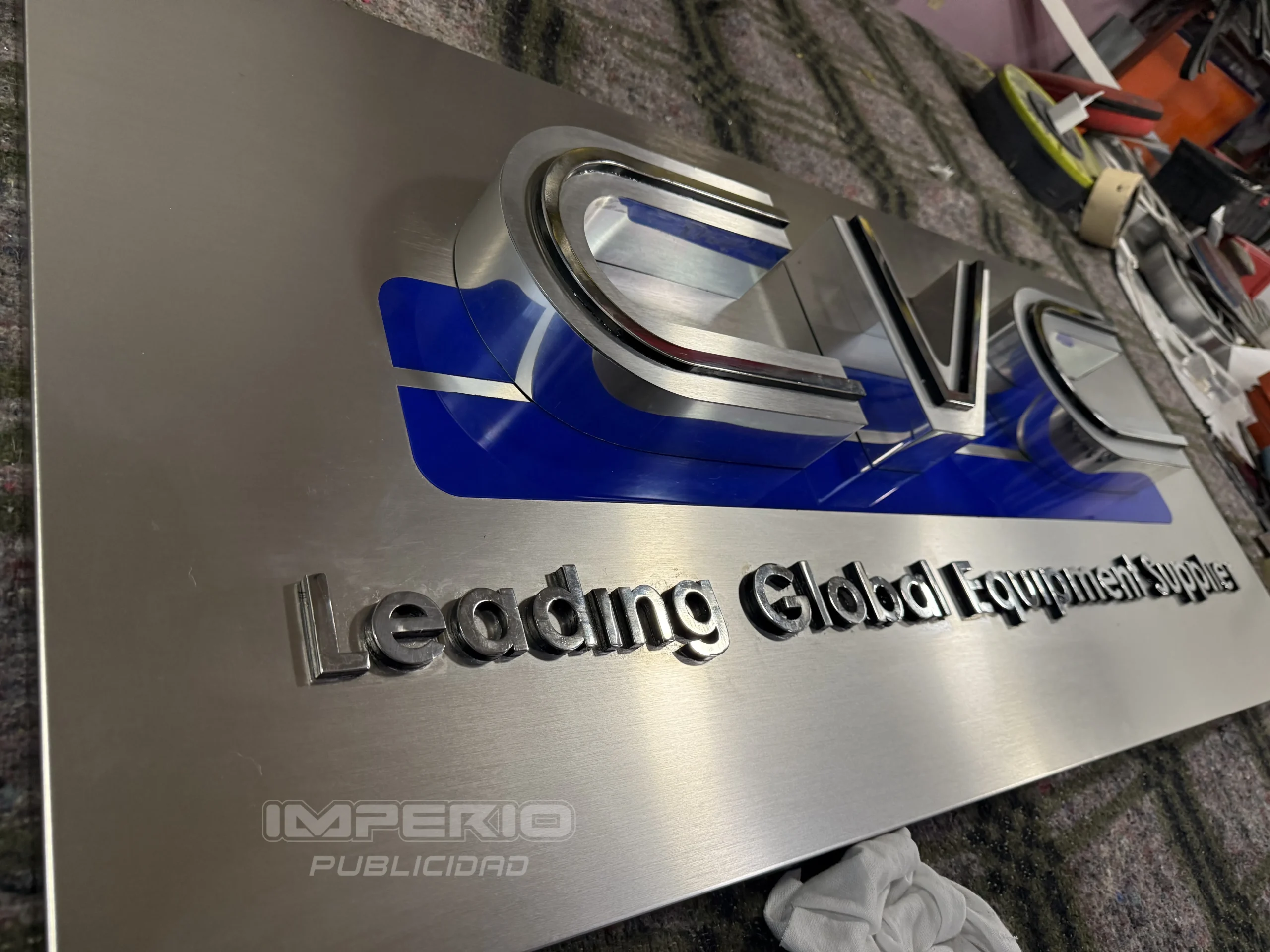Proceso de fabricación de letrero 3D en acero cepillado con acrílico azul y letras corpóreas CVC, realizado por Imperio Publicidad CDMX.