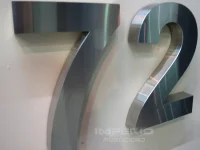 numeros-3d-acero-inoxidable-acabado-pulido-espejo-cdmx Números 3D de acero inoxidable con acabado pulido espejo instalados sobre muro blanco en CDMX