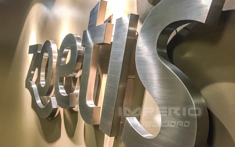 Letras 3D en acero inoxidable cepillado con iluminación halo LED instaladas en recepción corporativa en CDMX