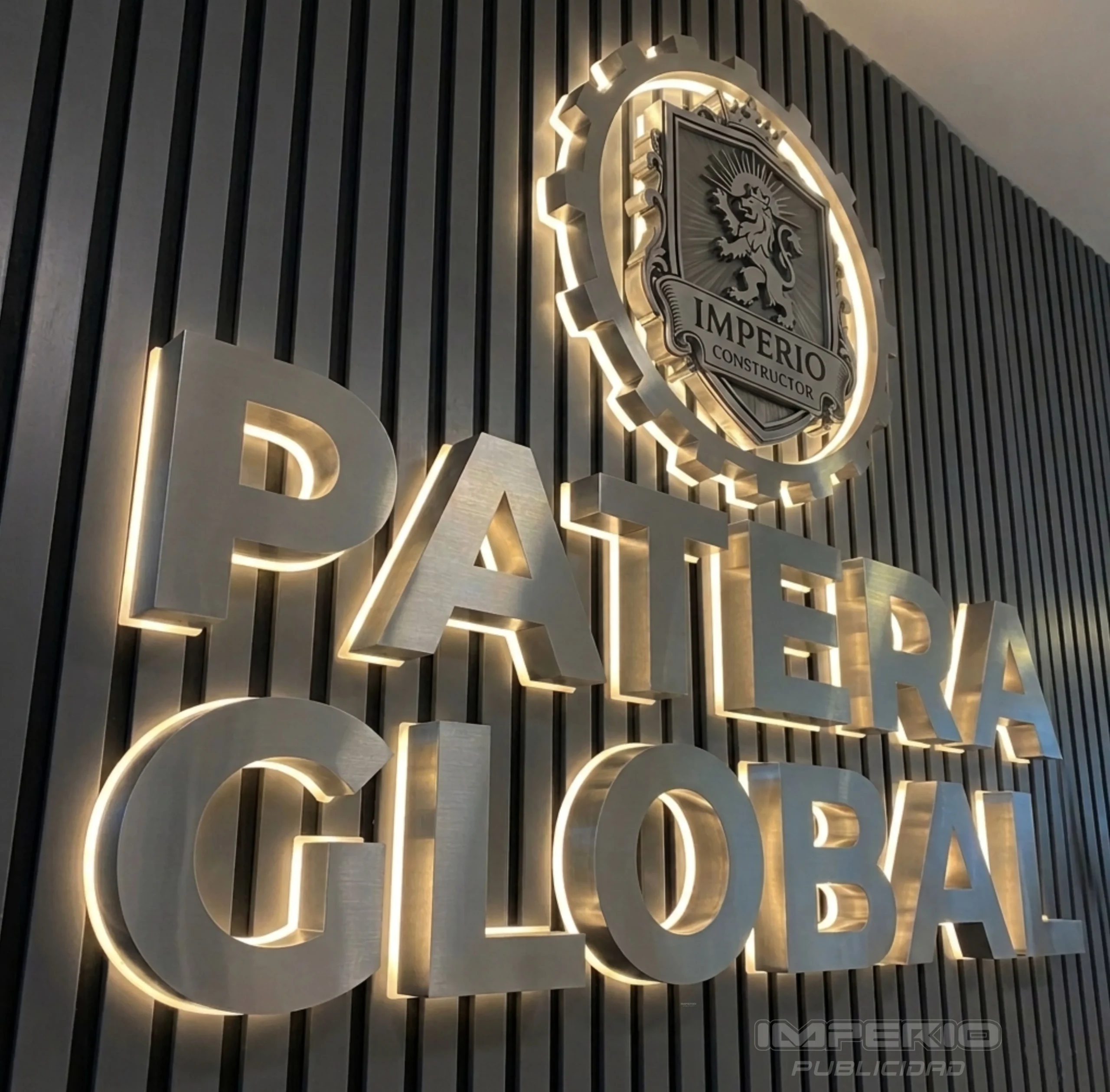 letras 3D de aluminio cepillado con iluminación halo LED y logotipo corporativo en muro moderno