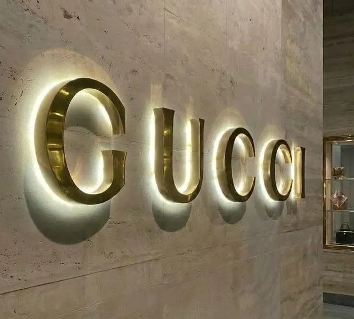 Letras 3D de aluminio dorado con iluminación halo LED cálido en muro de recepción estilo lujo en CDMX