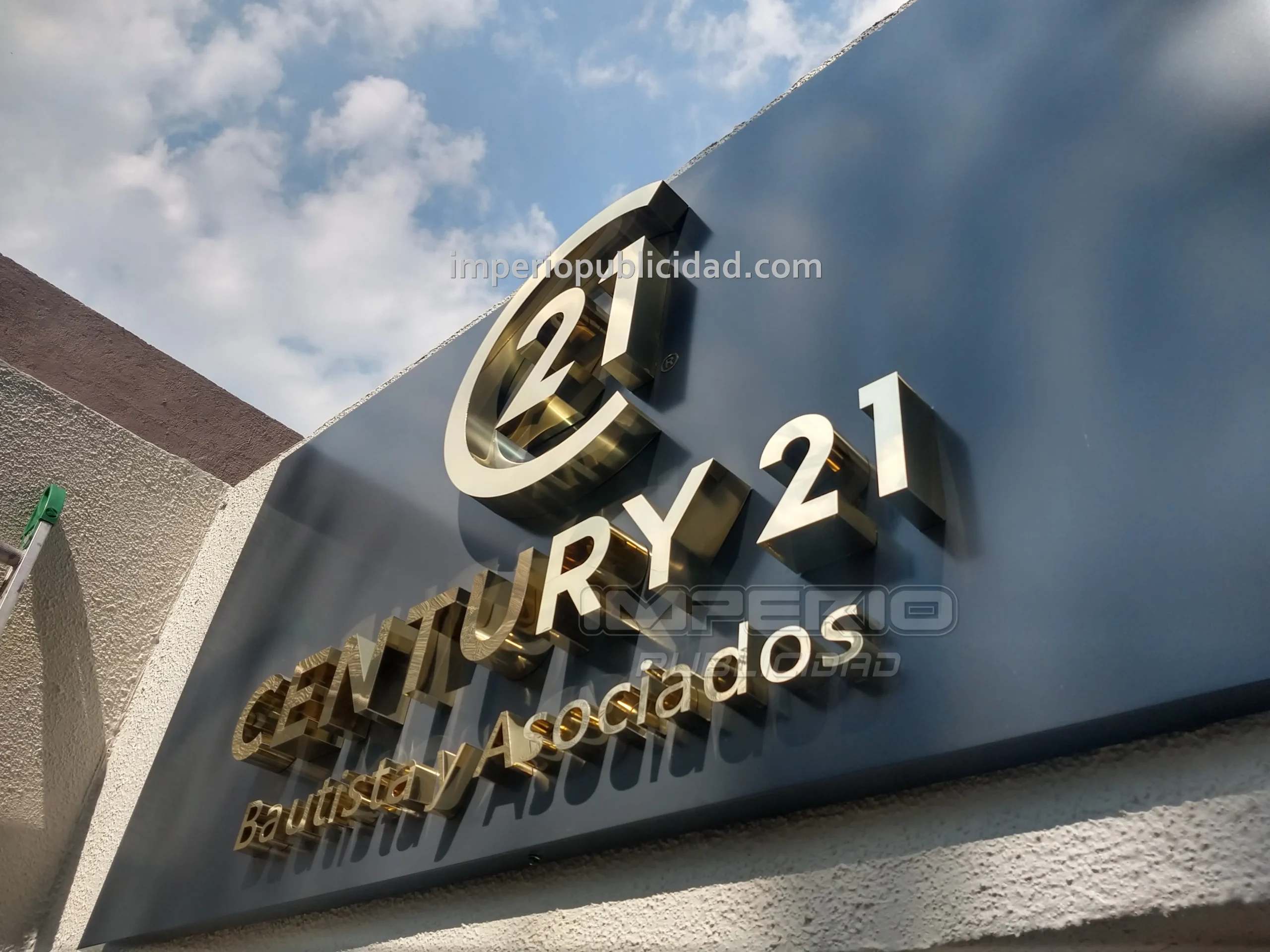 Logotipo Century 21 en letras 3D de aluminio dorado instalado en fachada de negocio
