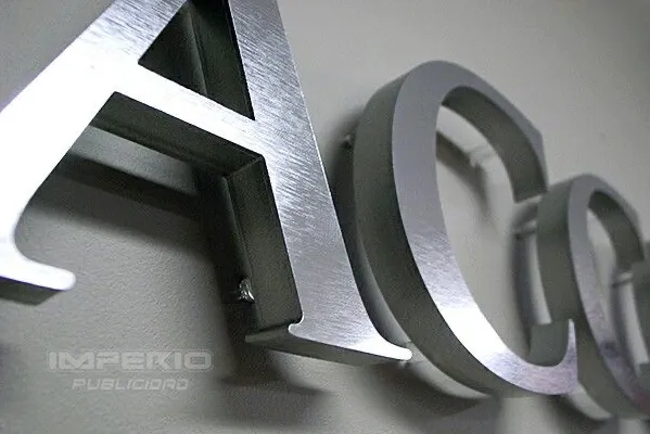 alt: letras 3d de aluminio plata cepillado instaladas en fachada de negocio con acabado elegante y relieve