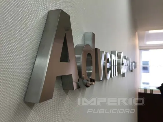 Letras 3D en acero inoxidable cepillado instaladas en muro interior de oficina corporativa en CDMX